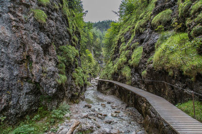 High angle view of boardwalk by stream amidst rock formations