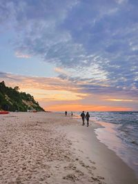 People on beach against sky during sunset