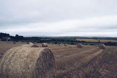 Hay bales on field against sky