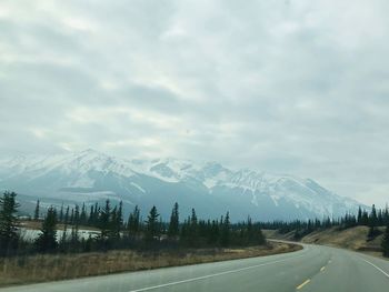 Road by snowcapped mountains against sky