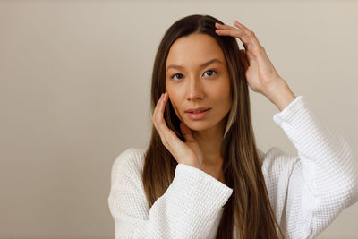 Portrait of young woman standing against wall