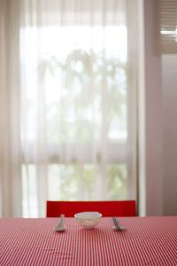 Empty bowl by spoon and chopsticks on table at home