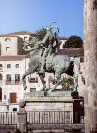 Statue by historic building against clear sky