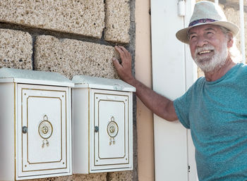 Smiling man looking away while standing by wall