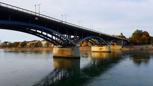 Bridge over river in city against sky