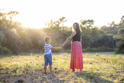 Woman and kid holding hands on a meadow