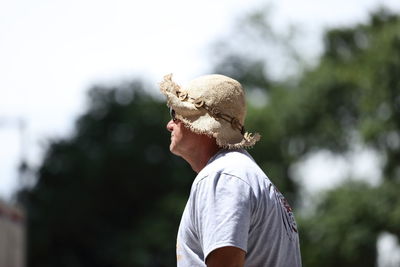 Side view of man standing against tree