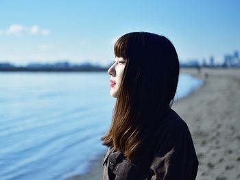 Portrait of young woman looking away against sky