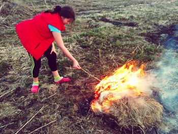 Teenage girl burning dry grasses on field