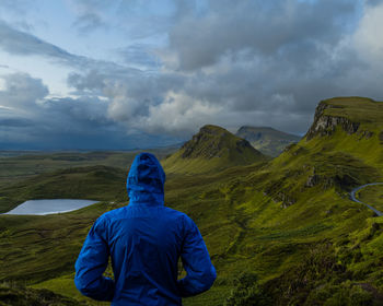 Rear view of man standing on mountain against sky