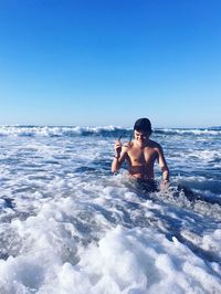 Shirtless man in sea against clear sky