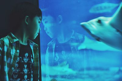 Boy looking at fish swimming in aquarium