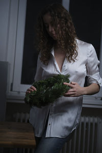 Woman holding wreath while standing at home