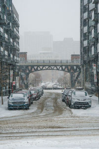 Cars on road in city against sky during winter