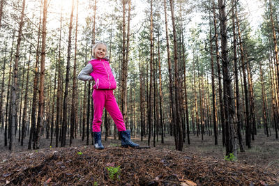 Full length portrait of girl standing amidst trees in forest