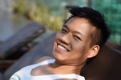 Portrait of smiling young man relaxing on chair outdoors