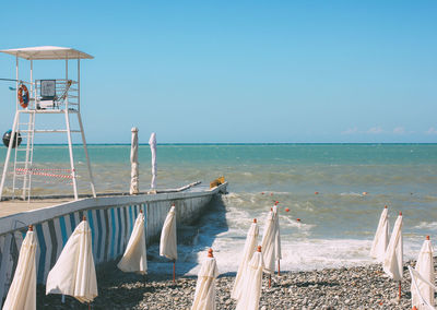 White empty booth tower on the shore of storming sea, closed empty beach