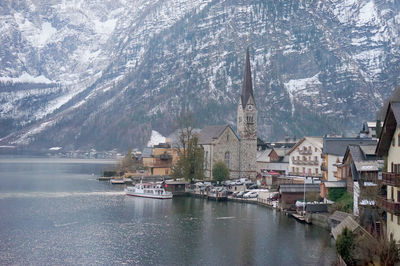 Buildings by lake in city during winter