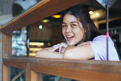 Portrait of smiling young woman sitting on wood