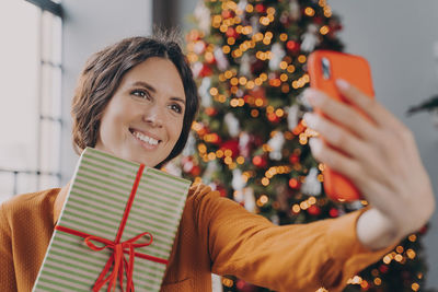 Smiling woman doing selfie while holding box