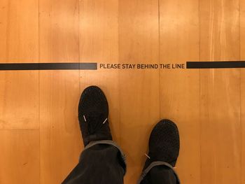 Low section of man standing on wooden floor