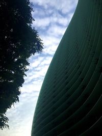 Low angle view of trees against cloudy sky