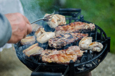 Cropped hand of man preparing meat on barbecue