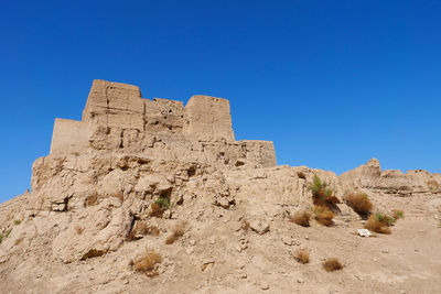 Low angle view of rock formations against clear blue sky