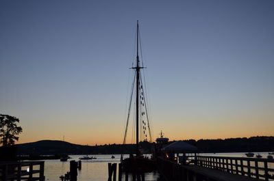Silhouette sailboats moored on shore against clear sky during sunset
