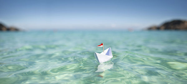 Close-up of paper floating on sea against sky