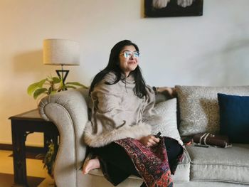 Young woman sitting on sofa at home