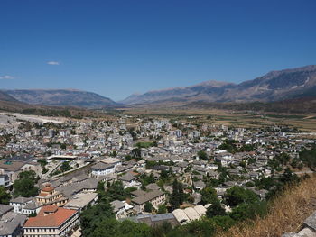 Aerial view of townscape and mountains against clear blue sky