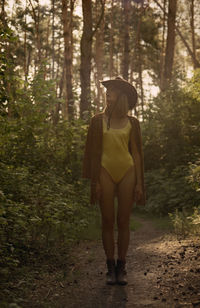 Rear view of woman standing in forest