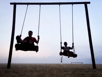 Two men sitting on swing