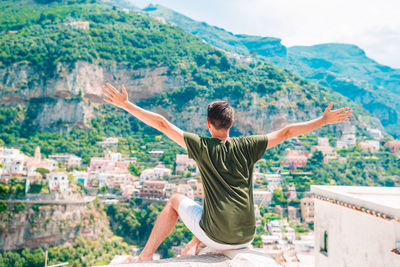 Young man with arms outstretched against mountain