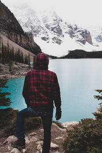 Rear view of man looking at lake during winter