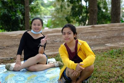 Portrait of female friends sitting on field at park