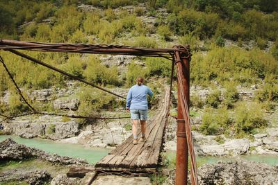 Rear view of woman walking on footbridge