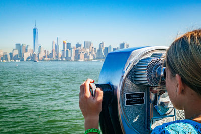 Man photographing by cityscape against clear sky