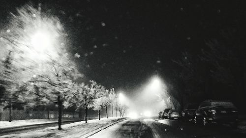 Road amidst trees against sky at night