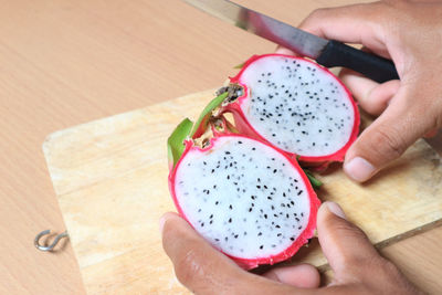 High angle view of hand holding fruits on cutting board