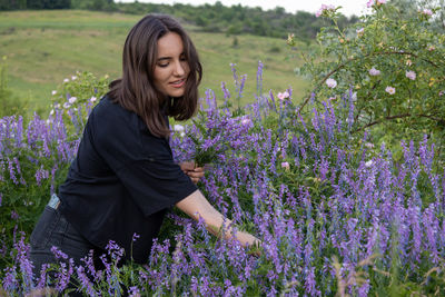 Portrait of young woman standing amidst plants on field