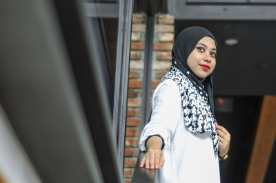 Young woman looking away while standing on railing