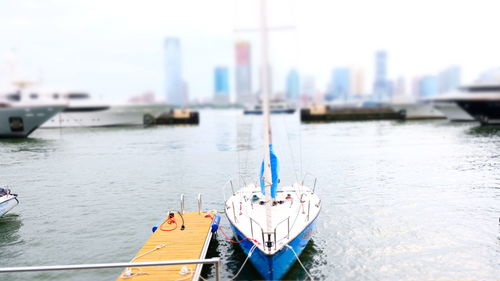 Boats moored in river by city against sky