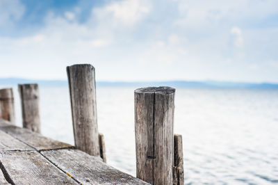 Wooden post on pier at sea against sky