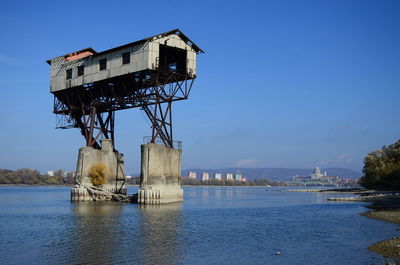 Abandoned stilt house in lake against sky