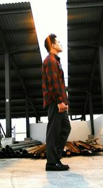 Side view of man standing against building
