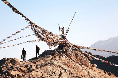 Low angle view of men against mountains against clear sky