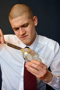 Man holding ice with coins against black background