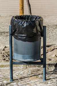 Close-up of garbage bin on footpath against wall